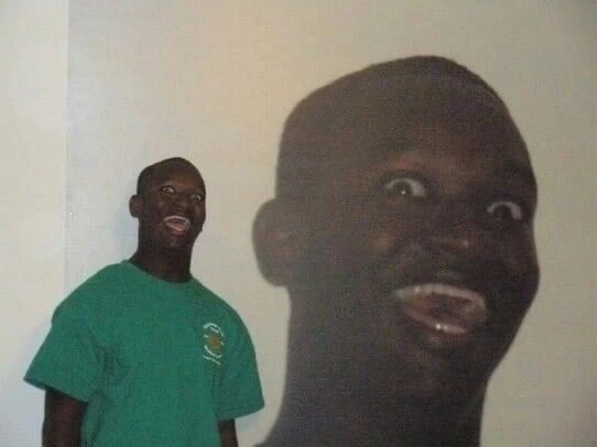 Black guy smiling creepy with his head displayed on the wall behind